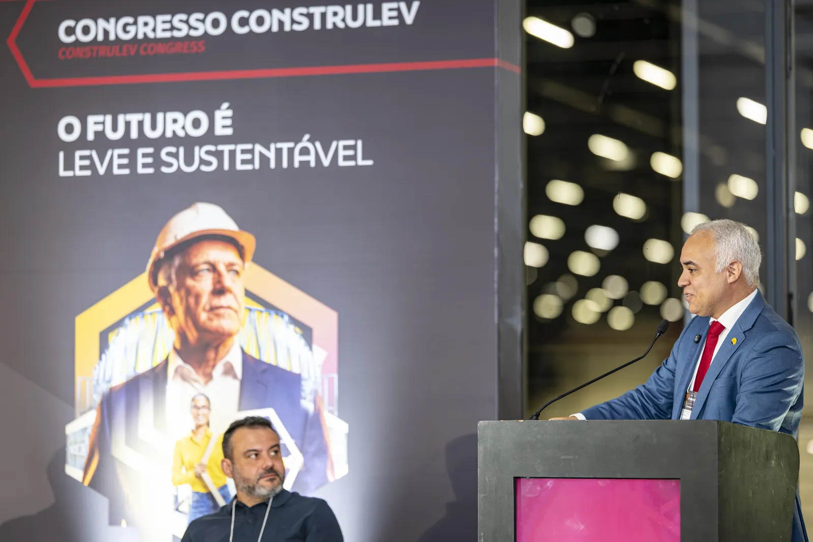 Palestrante no palco do Congresso Construlev 2026, com o painel "O futuro é leve e sustentável" ao fundo